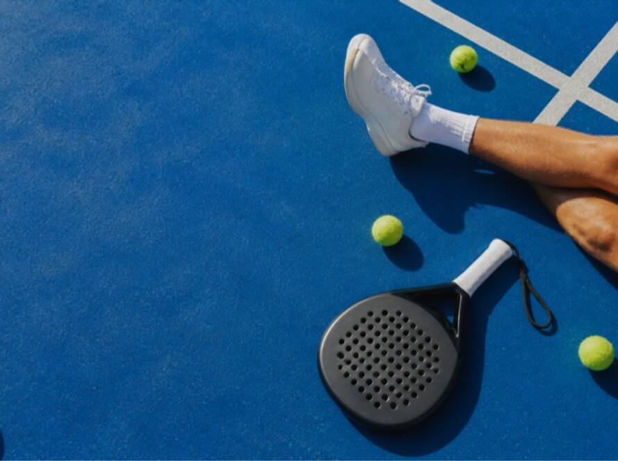 Padel-Schläger und Bälle auf blauem Padel-Court